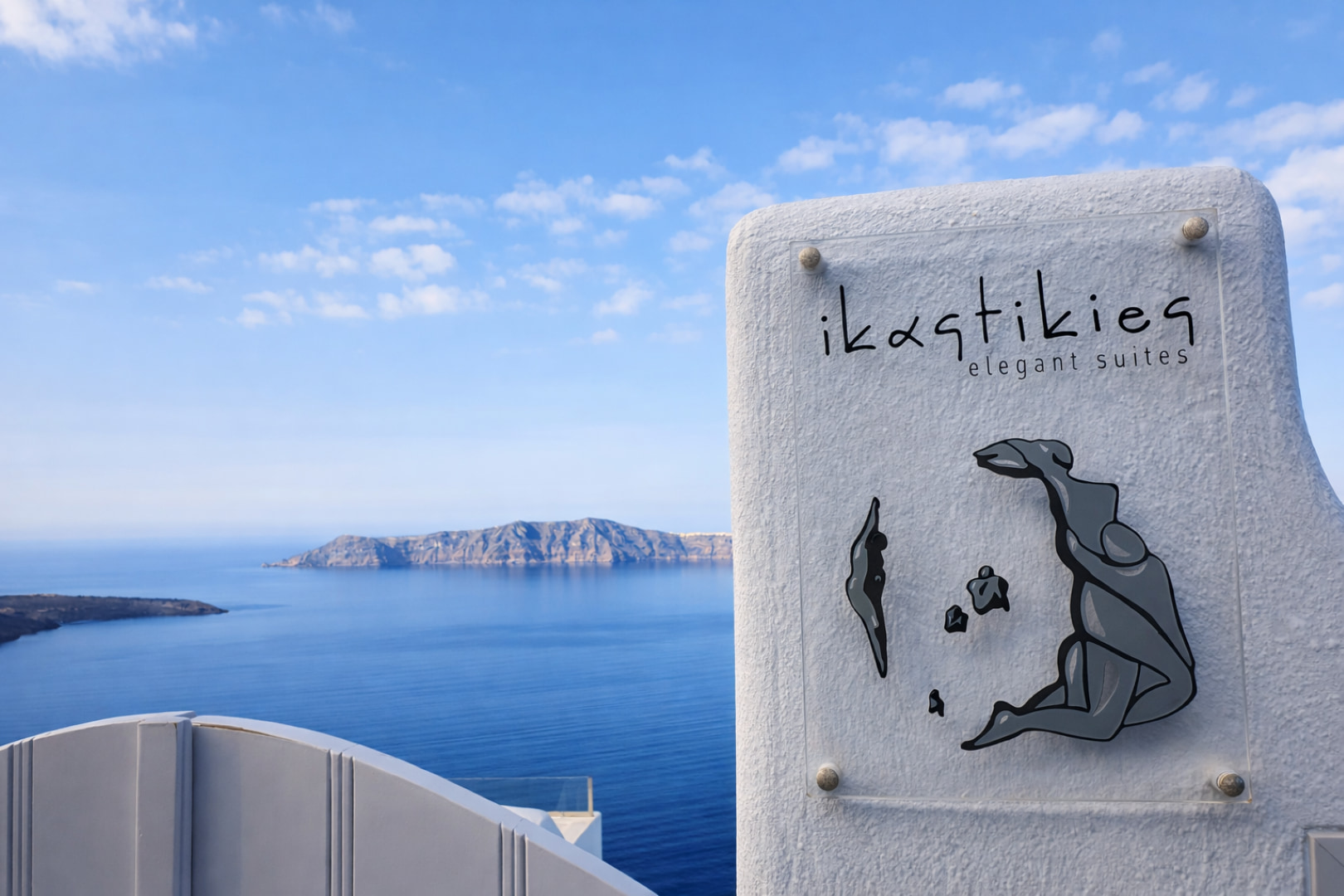 Ikastikies Suites exterior sign and entrance with Santorini caldera backdrop