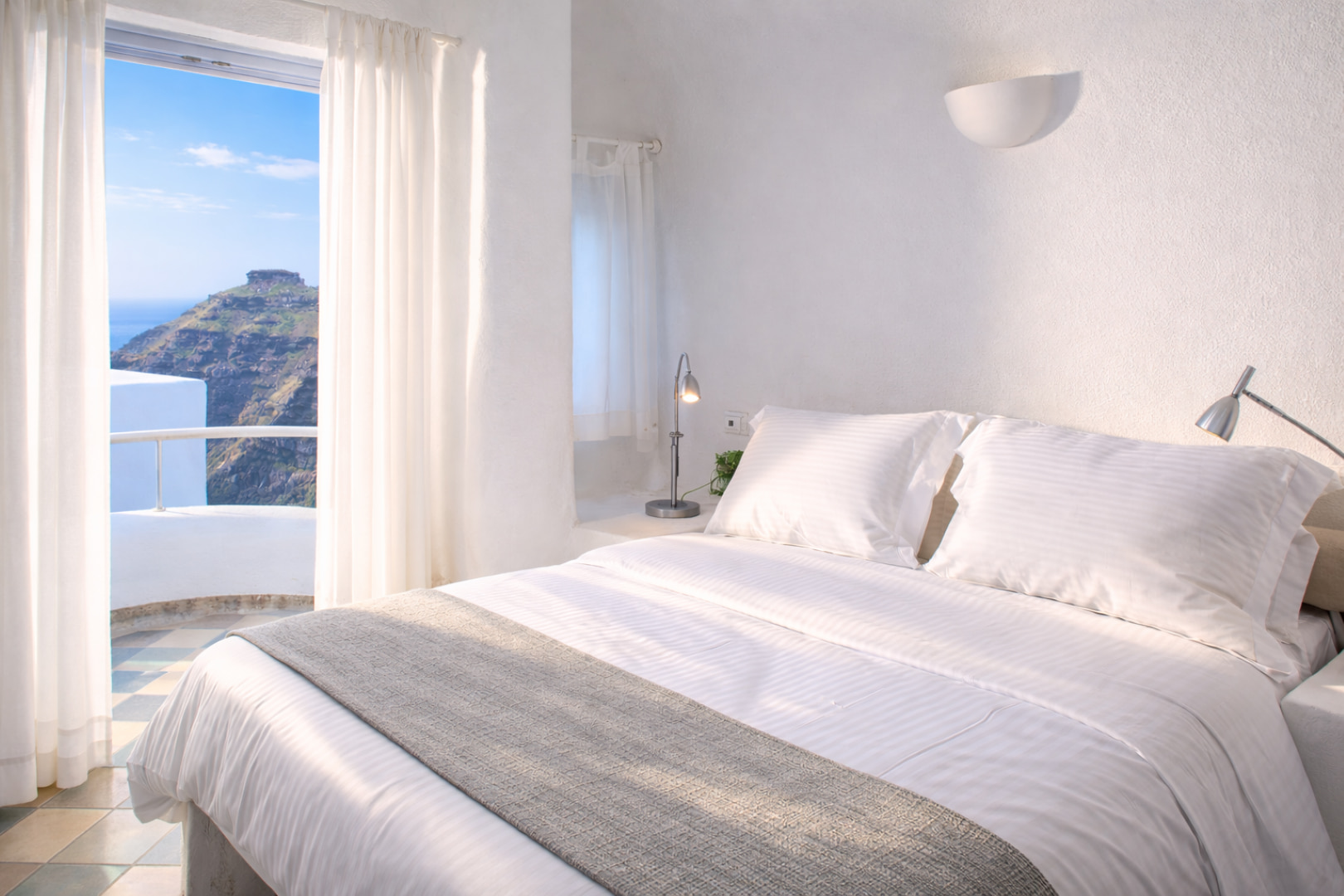 Soft white linens and king-size bed in Ikastikies Suites Santorini